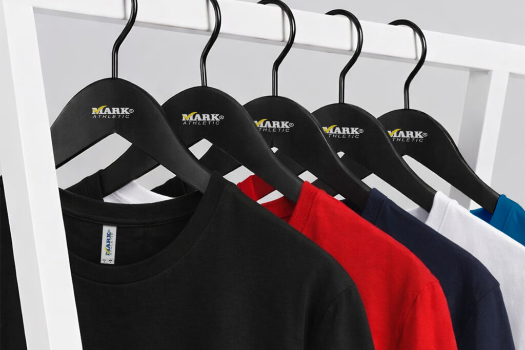 Playeras 9901 peso medio lisas en colores negro, rojo, marino y blanco colgadas en perchero minimalista