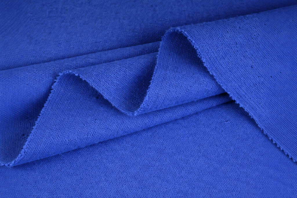 Detalle de tela azul tipo algodón peinado con textura visible y pliegues suaves, fotografía macro de alta calidad